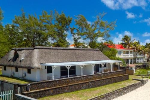 an old white house with a thatched roof at La Plage I Beachfront Villa on the Lagoon in Centre de Flacq