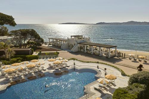 a pool with chairs and umbrellas next to the ocean at COMO Le Beauvallon - Golfe de Saint-Tropez in Grimaud