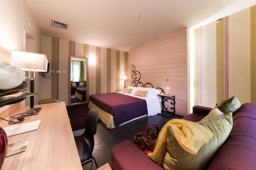 une chambre d'hôtel avec un lit et un canapé dans l'établissement El Homs Palace Hotel, à Comiso