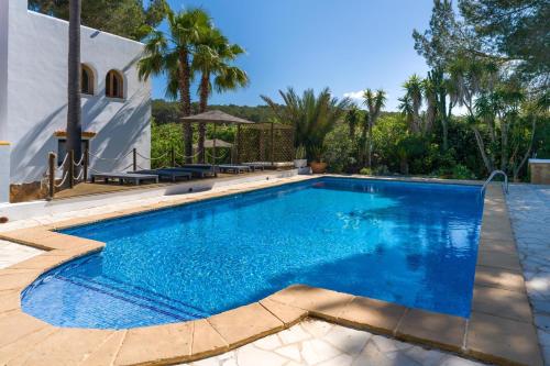 a swimming pool with blue water in front of a house at Asteria Eco Finca Sustainable 6 Bedroom Nature Retreat near UNVRS Ibiza in Santa Gertrudis de Fruitera