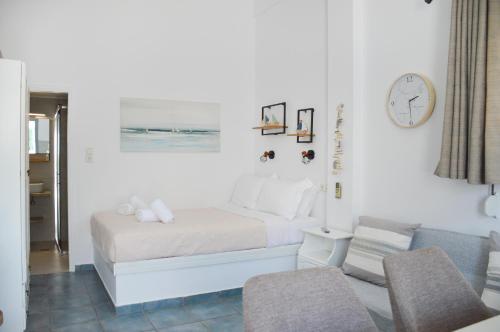 a white bedroom with a bed and a chair at Giorgantis Studio II in Plaka Milou