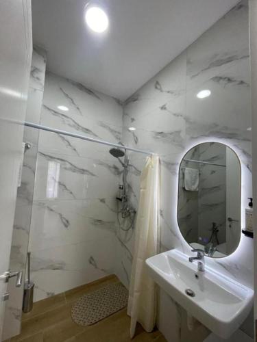 a white bathroom with a sink and a mirror at Enea Apartments 9 in Tirana
