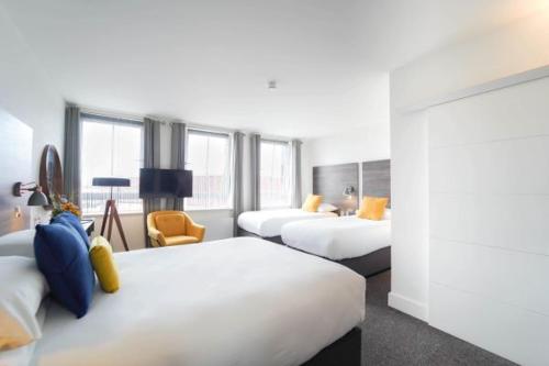 a hotel room with three beds and a chair at Base Dingle in Dingle