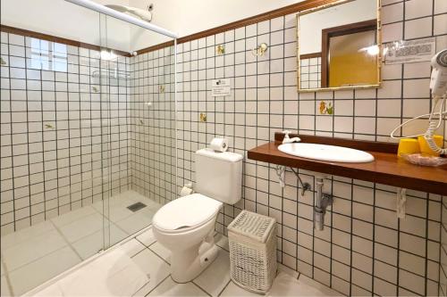 a bathroom with a toilet and a sink and a mirror at Pousada Fruto do Mar in Ilhabela
