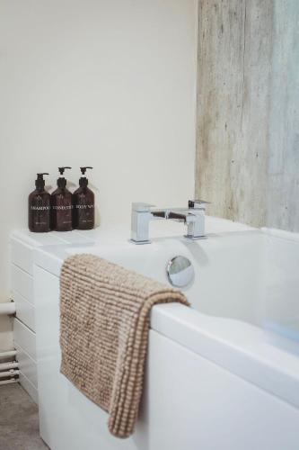 a white bathroom with a sink and a towel at Plasbach Cottage in Llandeilo