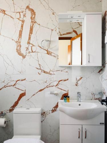 a bathroom with a white toilet and a sink at Corner Hotel in Ksamil