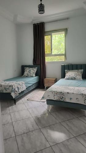 a bedroom with two beds and a window at Location saisonnière entre mer, forêt et calme in Raʼs al Jabal