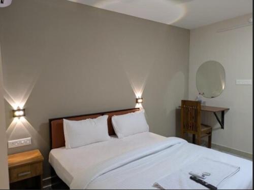 a bedroom with a large white bed with two lights at Hotel Vista by Booksy One Kollam Near Kollam Bypass in Kollam