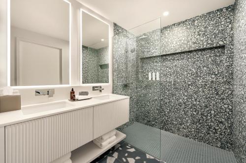 a bathroom with a shower with a sink and a mirror at ONE GT Grand Cayman in George Town