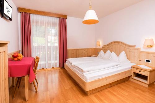 a bedroom with a white bed and a table with a red table at Garni Rives in Ortisei