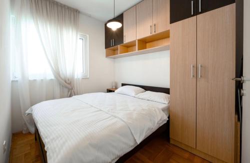 a bedroom with a large white bed and wooden cabinets at Aurea Tivat Apartment in Tivat