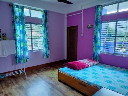 a bedroom with a bed and purple walls and windows at Nima homestay in Dirang Dzong