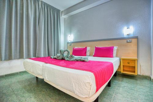 a bedroom with a large bed with pink pillows at RT-Green Park in Playa del Ingles