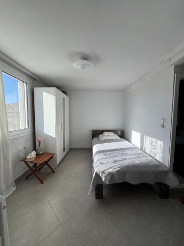 a white bedroom with a bed and a table at Romanou Guest House in Romanón