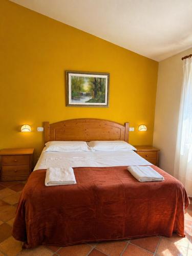 a bed in a yellow room with two towels on it at I Cancelli -Mugello Park Family Village in Palazzuolo sul Senio