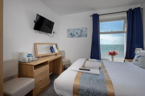 a bedroom with a bed and a desk and a window at Hotel Santa Maria in Blackpool