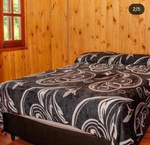 a black and white bed in a wooden room at Complejo Bellotas in Agua de Oro