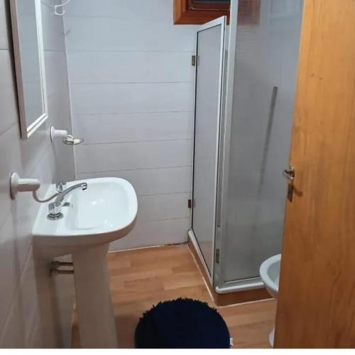 a bathroom with a white sink and a shower at Complejo Bellotas in Agua de Oro