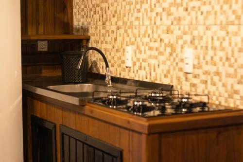 a kitchen counter with a stove and a sink at Recanto Deucher in Imaruí