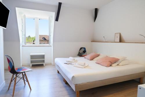 a bedroom with a bed and a chair and a window at Hôtel Restaurant Le Commerce in Navarrenx