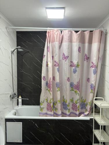 a bathroom with a shower curtain with butterflies on it at Omurbek Guesthouse in Sary-Mogul