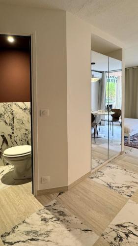 a bathroom with a toilet and a room with a table at Cozy Studio, Pool & Beaches 2 min away in Roquebrune-Cap-Martin