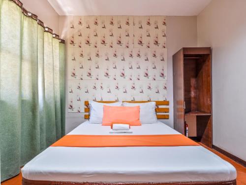 a bedroom with a bed with an orange pillow at California Signature Suites in Sudtungan