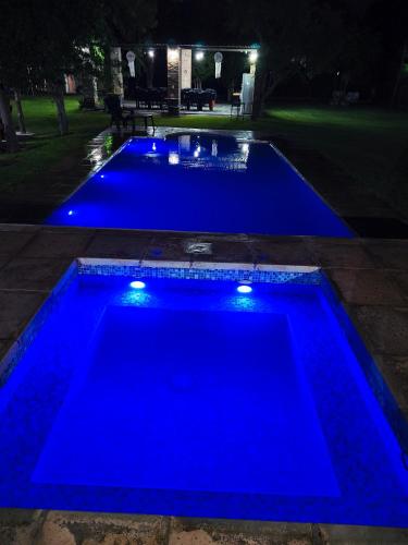 a blue pool with lights in a backyard at night at finca granja la soñadita in Santiago del Estero