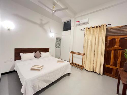 a bedroom with a bed with white sheets and a window at Lumieri Hotel Arugambay in Arugam Bay