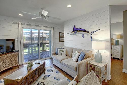 a living room with a couch and a fish on the wall at Bay Tree A3 in Port Aransas