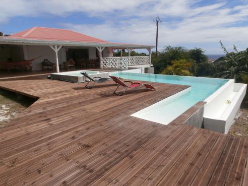 a wooden deck with a swimming pool and a house at Villa Alizea in Capesterre-de-Marie-Galante