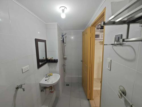 a white bathroom with a sink and a shower at Steve's Condo in Davao City