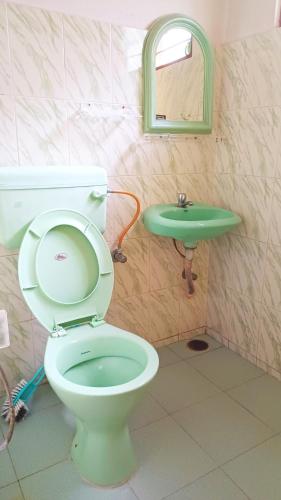 a bathroom with a toilet and a green sink at Ganesh House Homestay in Kovalam