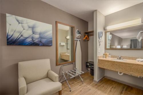 a bathroom with a sink and a mirror and a chair at Baymont by Wyndham Socorro in Socorro