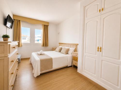 a white bedroom with a bed and a door at G&G Isla Marina Puerto in Benalmádena