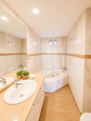 a bathroom with a sink and a tub at G&G Isla Marina Puerto in Benalmádena