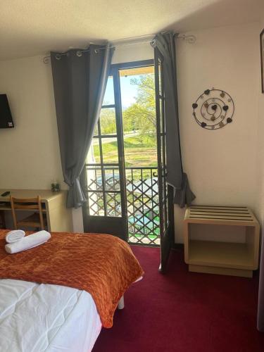 a bedroom with a bed and a door to a balcony at HUMAN HOTEL RESTAURANT Park in Villecroze