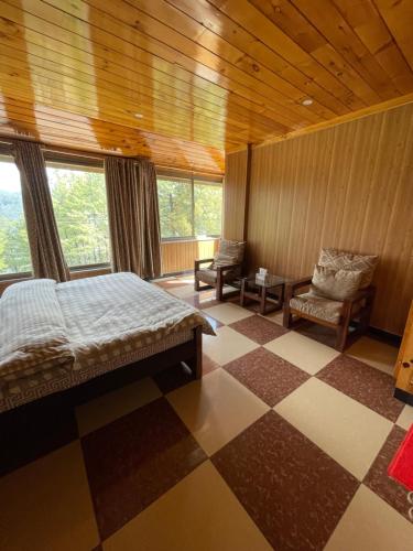 a bedroom with a bed and a chair and windows at Hillside Cottages, Kala Bagh in Nathia Gali