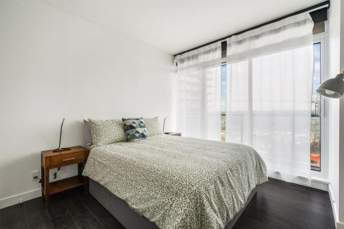 a bedroom with a bed and a large window at Bright & Cozy 1BR Steps to Brentwood mall in Burnaby