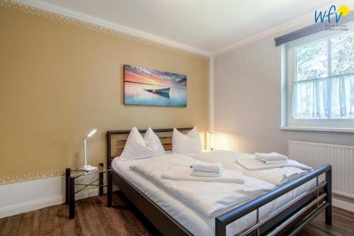 a bedroom with a bed with white sheets and a window at Haus Wreechen Ferienwohnung Michaelis in Putbus