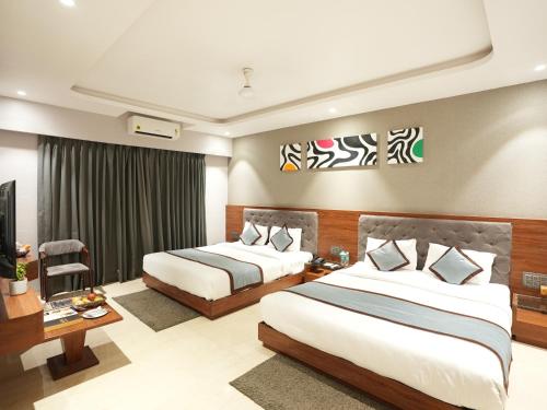a hotel room with two beds and a television at Alaukik Hotel in Shirdi