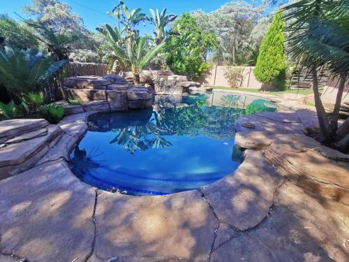 a swimming pool in a backyard with a rock bridge at Rondevue Game Lodge in Warmbaths