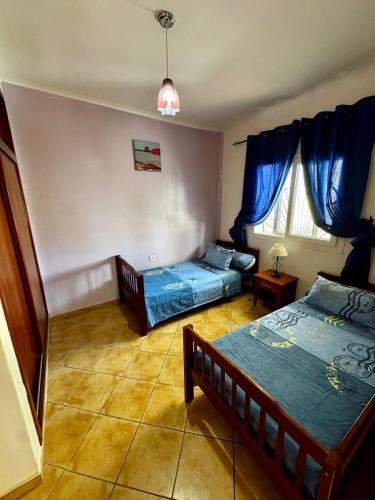 a bedroom with two beds and a window with blue curtains at Peaceful Haven with Pool, Breathtaking View in Oued Laou