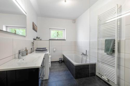 a white bathroom with a tub and a sink at Ferienwohnung Dicke Linde, 55qm in Schmallenberg