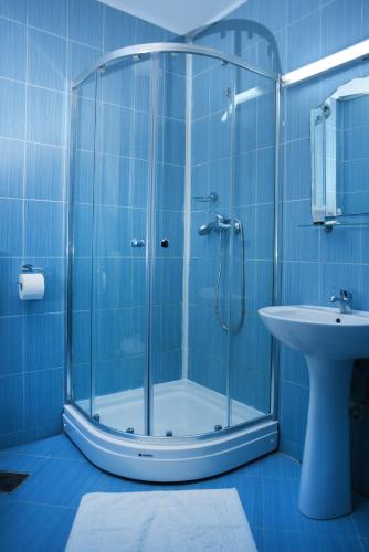 a blue bathroom with a shower and a sink at Hotel Vacanța in Geoagiu Băi