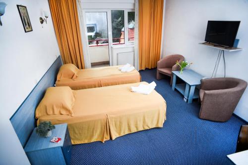a hotel room with two beds and a television at Hotel Vacanța in Geoagiu Băi