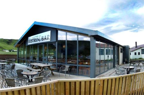 a restaurant with tables and chairs on a deck at Hótel Skógafoss by EJ Hotels in Skogar