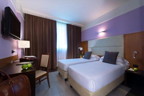a hotel room with two beds and a desk at My One Hotel Bologna in Bologna