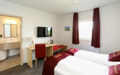 a hotel room with two beds and a desk and a television at Hótel Eyjafjallajökull in Hvolsvöllur