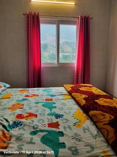 a bed with a colorful comforter in front of a window at Brooklyn Homestay in Vattavada